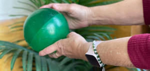 Persona mayor realizando ejercicio físico con una pelota para un envejecimiento activo y saludable.